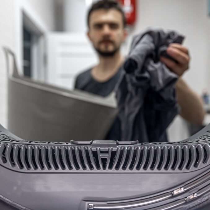 man-holding-dirty-cloth-hand-view-inside-washing-machine